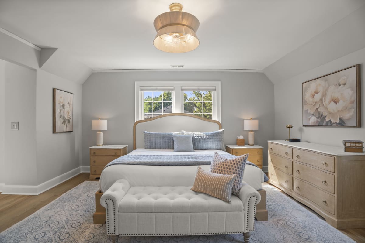 Unwind in your elegant master bedroom retreat, with a plush bed, soft linens, warm wood furniture, and natural light streaming through the windows.