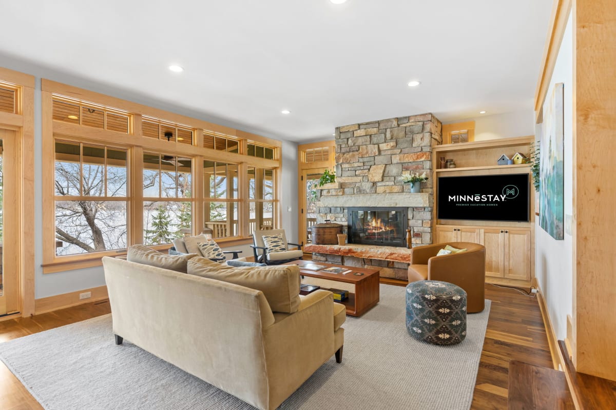 Sink into plush seating by your stone fireplace, where warm wood tones and panoramic windows create the perfect retreat.