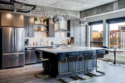 Contemporary kitchen with grey cabinets, white countertop, and stylish lighting.