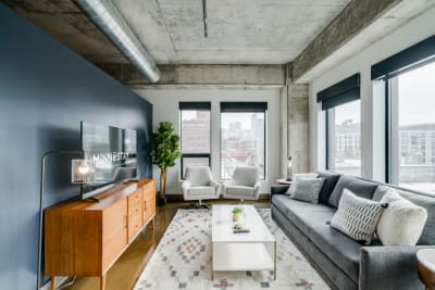 Contemporary living room featuring a deep blue wall, sleek furniture, and a city view from large windows.