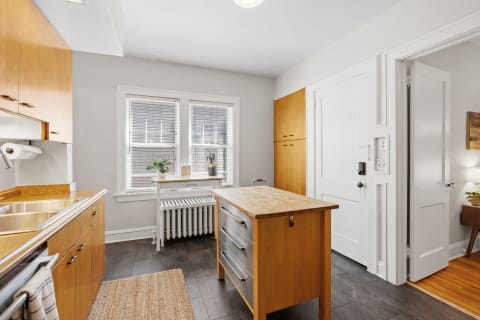 Modern kitchen with wooden cabinets, stainless steel sinks, and bright lighting.