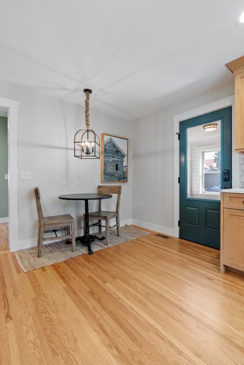 Cozy dining corner with a round table, two chairs, and a blue door.