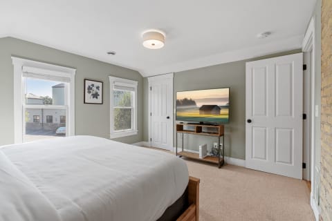 A cozy bedroom with a comfortable bed, a television, and soft green walls.
