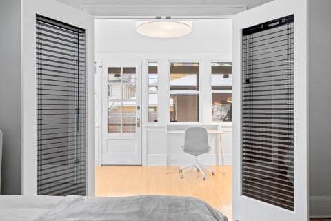 View from a bedroom into a bright workspace with a desk and chair.