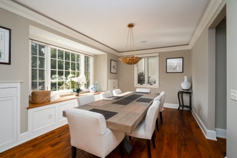 Contemporary dining room with a large table, soft chairs, and a golden chandelier.