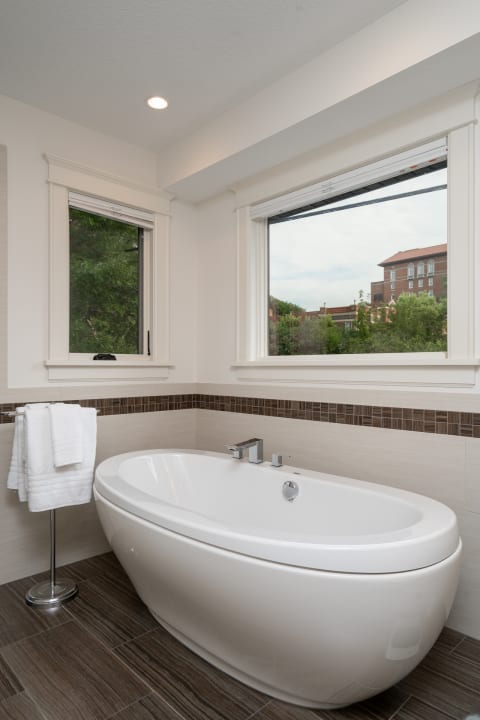 Modern bathroom with freestanding bathtub and large windows.