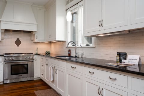 Modern kitchen with white cabinets, dark countertops, and stainless steel appliances.