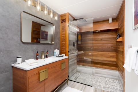 Modern bathroom with gray tiles, wood accents, and a glass shower.