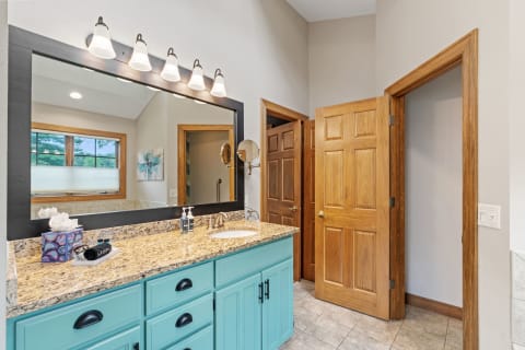 Modern bathroom with a turquoise double vanity and large mirror.