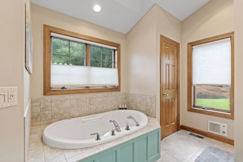 Corner bathtub in a serene bathroom with wood accents and natural light.