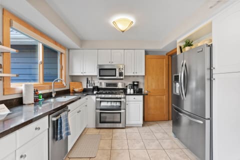 A well-designed kitchen featuring white cabinets, dark granite countertops, and stainless-steel appliances.