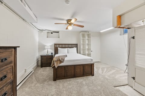 Cozy basement bedroom featuring a wooden bed, a nightstand, and soft carpeting.