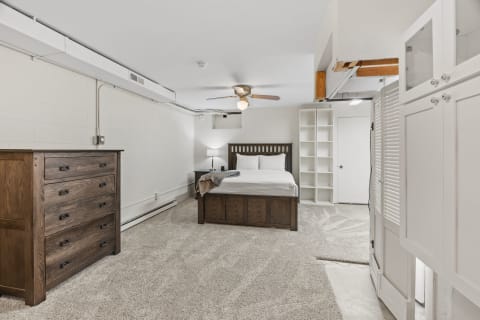 Cozy bedroom featuring a wooden bed frame, nightstand, dresser, and built-in shelves.