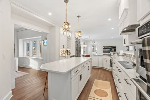 Modern kitchen with marble countertops and elegant pendant lighting.