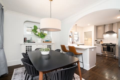A modern dining room featuring a black table, six black chairs, and a stylish pendant lamp.