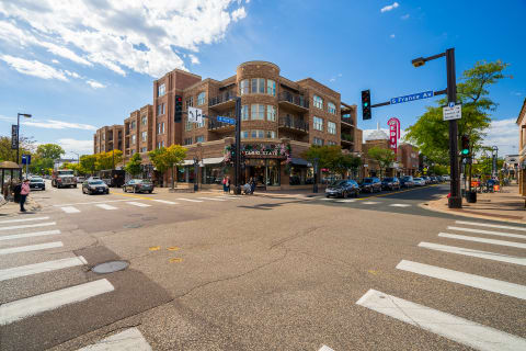 An urban intersection with vehicles, pedestrians, and modern brick buildings.