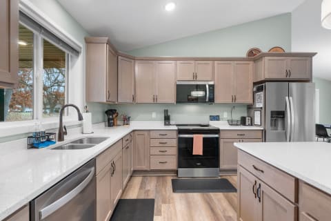 Modern kitchen with gray cabinets, white countertop, and stainless steel appliances.