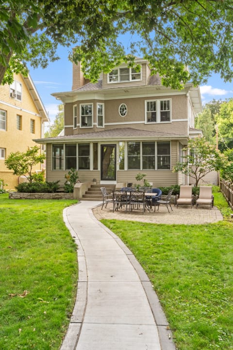 Exterior view of a charming multi-story house with a curved pathway and outdoor seating.