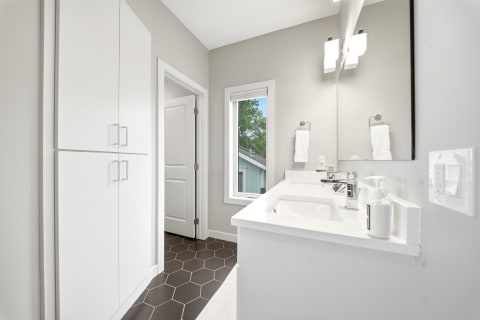 Modern bathroom with a spacious vanity, hexagonal tile floor, and natural light from a window.