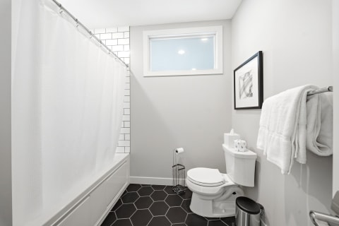 Modern bathroom with black hexagonal tiles, white subway tile shower, and minimalist decor.