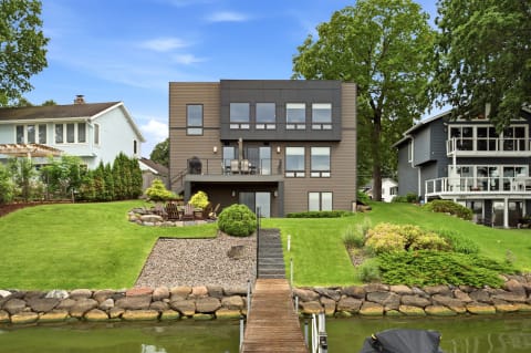 Contemporary three-story lakefront home with a private dock and landscaped backyard.
