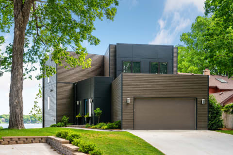 Contemporary house surrounded by greenery and large trees.