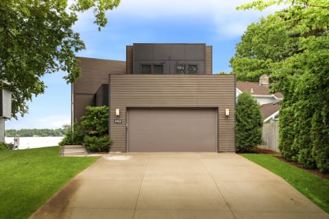 Contemporary two-story vacation home with a garage, nestled in green surroundings.