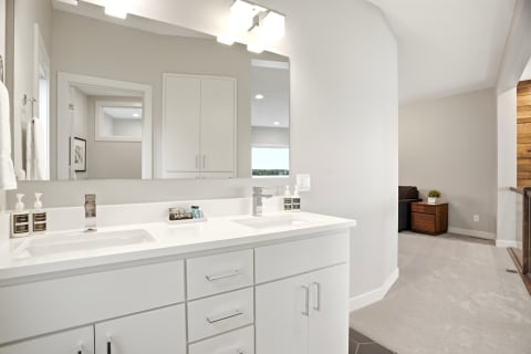 A spacious en-suite bathroom showcasing dual vanities, modern fixtures, and neutral decor.