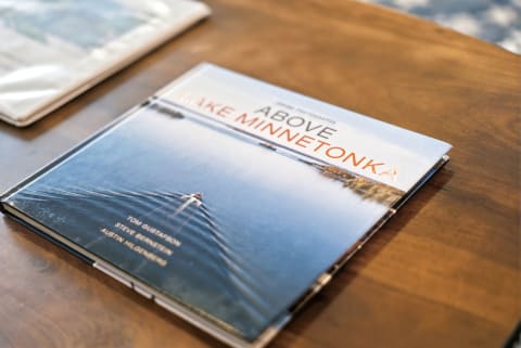 Book titled 'Above Lake Minnetonka' on a wooden table, featuring an aerial view of the lake.