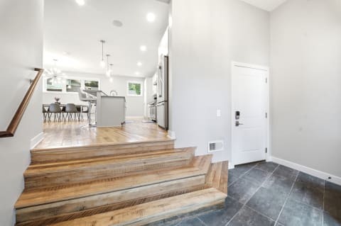 A well-lit entryway showcasing a staircase leading to a kitchen and dining area with modern furnishings.