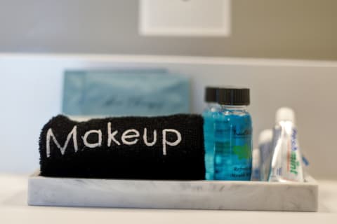 A black towel labeled 'Makeup' along with mouthwash and toothpaste on a marble tray in a bathroom setting.