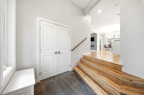 Modern entryway with tile flooring, hardwood stairs, and double doors.
