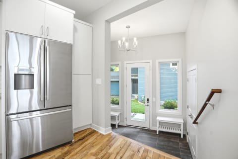 Stylish entryway with stainless steel refrigerator and bright natural light.