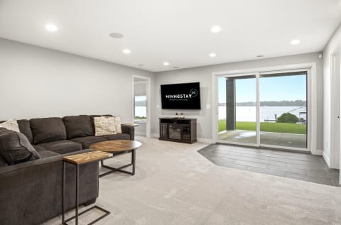 A spacious living room featuring a sectional sofa and a large window with a waterfront view.