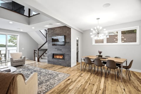 A modern living room featuring a fireplace, stylish chairs, and a dining table with natural light flooding in.