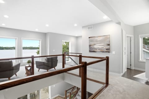 A spacious loft with modern design, featuring two chairs, large windows, and lake views.