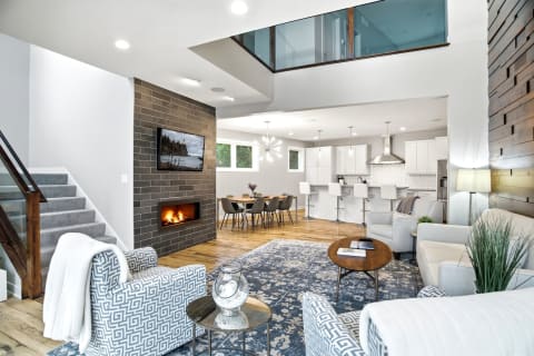 Modern open-concept living room with a cozy fireplace, stylish furniture, and an airy dining area.