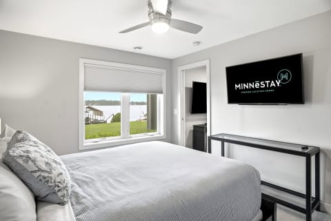 Cozy bedroom with a view of a lake and a modern TV.