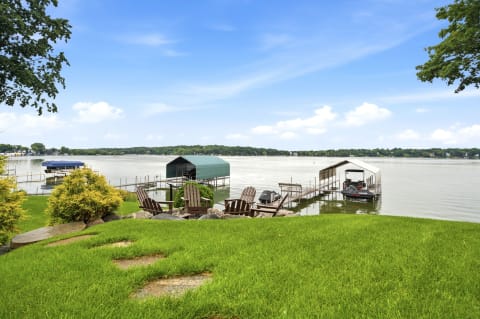 Lakefront property with Adirondack chairs, boat slips, and a scenic view of the water.