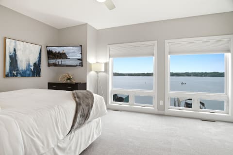 A cozy bedroom with a view of the lake and stylish decor, featuring large windows and calming colors.