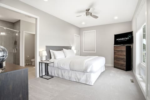 Modern bedroom with king-sized bed, TV, and en-suite bathroom visible.
