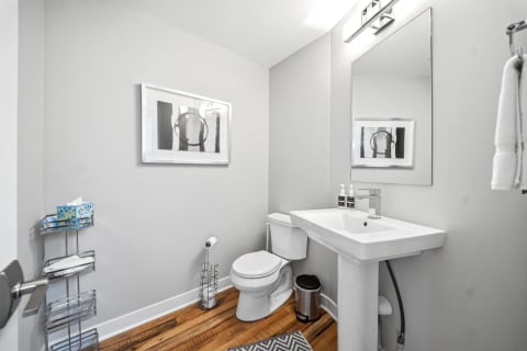 Contemporary bathroom with gray walls, hardwood flooring, and modern fixtures.