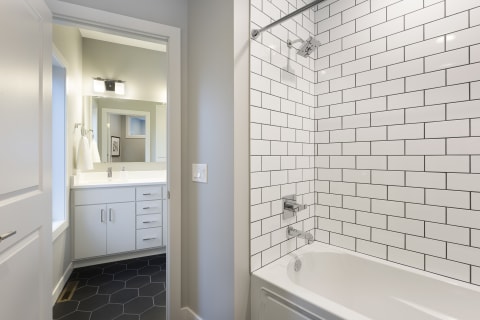 Modern bathroom with white subway tile and hexagonal black flooring.
