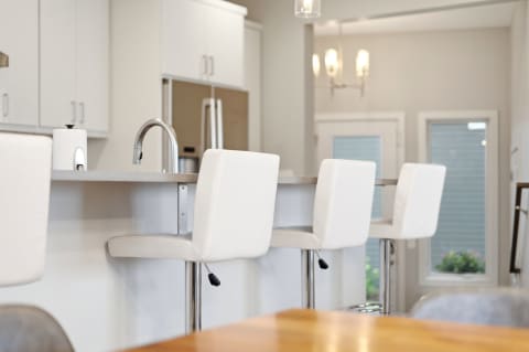 Bright modern kitchen with white bar stools at a stylish breakfast bar.