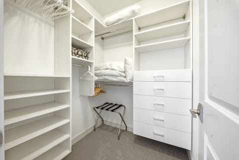 Spacious walk-in closet featuring built-in shelves, hanging rods, and a modern dresser.