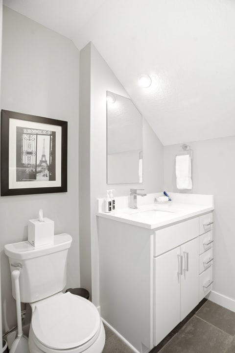 Modern bathroom with minimalist design featuring a vanity, mirror, and artistic wall art.