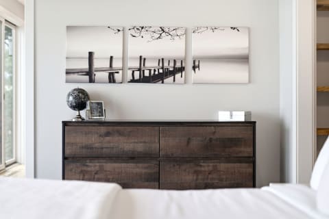 A cozy bedroom scene with a wooden dresser, serene lake artwork, and a globe decoration.