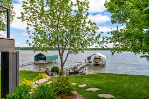 Lakeside scene featuring docks, a boat, and green lawns.