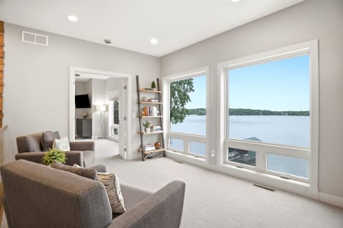 Bright living room featuring large windows with a beautiful view of the lake and modern furnishings.
