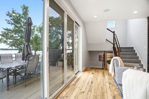 Interior space with hardwood floors and glass doors leading to a deck overlooking water views.